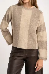 Sweater de tejido grueso con diseño de bloques verticales y horizontales en tonos beige y marrón. Tiene cuello redondo y mangas largas.