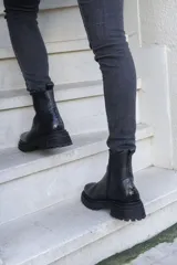 Botas de cuero negro con punta cuadrada, caña media y cierre lateral con cremallera.