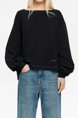 Camiseta negra de manga larga con corte holgado, cuello redondo y pespuntes a contratono.