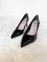 Zapato de tacón alto Iara, color negro charol, con punta fina y suela roja. Fabricado en cuero.