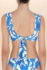 Top de bikini blanco con estampado de hojas y flores azules, de corte cruzado y breteles anchos.