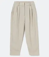 Pantalón zanahoria color beige de liocel, con pliegues delanteros, bolsillos laterales y cierre con cremallera y botón.