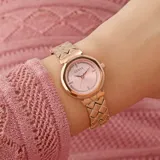 Reloj Guess con caja redonda y malla de acero inoxidable color oro rosa. El dial es rosa con indicadores de cristal.