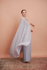 Vestido largo de encaje color plata con brillos y cuello halter. Incluye capa de gasa larga.