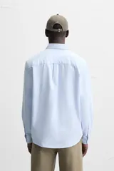 Camisa azul marino de corte regular fit, confeccionada en tejido de algodón Oxford. Tiene cuello abotonado, manga larga con puños abotonados, bolsillo de parche en el pecho y cierre frontal con botones.