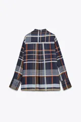 Camisa de mujer confeccionada en viscosa con estampado a cuadros en tonos azul, naranja, blanco y amarillo. Tiene cuello mao, manga larga con puños plisados, dos bolsillos de parche con solapa en el pecho, bajo recto y cierre frontal con botones ocultos.
