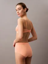 Conjunto Calvin Klein color durazno, compuesto por un corpiño triangular de algodón con breteles finos y una bombacha hípster de algodón con cintura elástica.