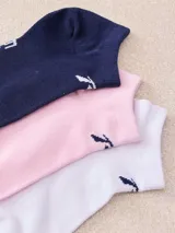 Pack de tres medias tobilleras de algodón, una en color lila, una amarilla y una blanca. Todas tienen un pequeño logo bordado en color violeta.