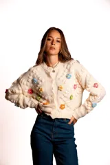 Saco de punto color rojo, con cuello polo y cierre frontal de botones blancos. Presenta flores bordadas en relieve de diferentes colores (azul, amarillo, verde, naranja, rosado) y mangas largas con diseño de burbujas.