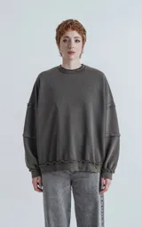 Buzo cuello redondo color gris oscuro con efecto desgastado, costuras expuestas y calce oversize crop.