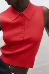 Top tejido de punto color rojo, sin mangas, con cuello polo y cierre frontal con botones.