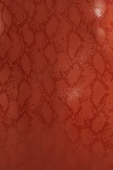 Malla enteriza color ladrillo con estampado de piel de serpiente, escote en V y espalda descubierta con tiras cruzadas unidas por un detalle metálico cuadrado.