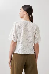 Blusa color crudo de broderie con escote en V y cierre frontal con lazos.