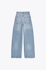 Pantalón de jean celeste de corte extra wide leg, tiro alto, cinco bolsillos, trabillas en la cintura y cierre con cremallera y botón metálico.