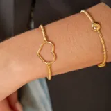 Pulsera dorada con malla extensible y dije de corazón calado.