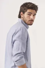 Camisa de lino color blanco, de corte regular, con cuello clásico y mangas largas.