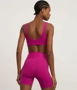 Conjunto deportivo de dos piezas, color fucsia vibrante, compuesto por un top deportivo de escote redondo y una bermuda ciclista de tiro alto.