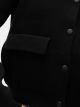 Cárdigan negro de punto con cierre de botones y bolsillos frontales. Confeccionado en mezcla de poliéster reciclado, poliéster y nailon.