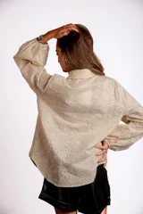 Camisa celeste con bordado de flores blancas, de manga larga abullonada.