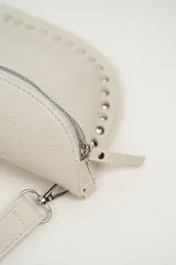 Riñonera negra de cuero sintético con correa ajustable y cierre superior con cremallera. Decorada con tachas plateadas en el borde inferior.