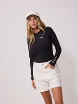 Remera de lycra negra de manga larga con protección UV y logo de la marca Rusty estampado en blanco en el pecho y en la manga izquierda.