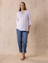 Blusa blanca de poliéster y rayón con escote en V bordado y mangas tres cuartos regulables con presilla y botón.