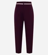Pantalón de vestir azul marino, de corte zanahoria, con cinturón fino negro con hebilla dorada.