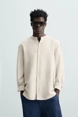 Camisa color beige claro de lino y algodón, corte relaxed fit, cuello mao, manga larga con puños abotonados y cierre frontal con botones. Marca Zara.
