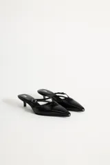 Zapato destalonado tipo mule de cuero negro, con punta fina, tira delantera con hebilla y tacón kitten.