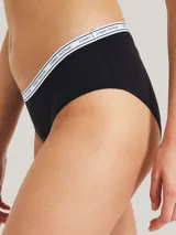 Bombacha hipster negra de algodón y elastano, con cintura elástica blanca con logo Tommy Hilfiger repetido.