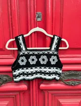 Top corto tejido al crochet, color negro con detalles en blanco y flores blancas.