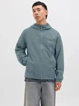 Campera softshell color celeste con capucha ajustable con cordón, mangas largas con puños de canalé, cierre frontal con cremallera y bolsillos delanteros.