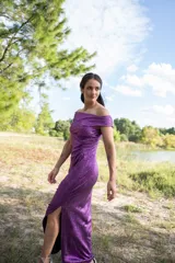 Vestido midi color violeta con textura brillante, escote off-shoulder y mangas cortas.