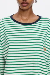 Camiseta de algodón con estampado de rayas horizontales verdes y blancas, cuello redondo con ribete azul marino, mangas largas y logo bordado en el pecho.
