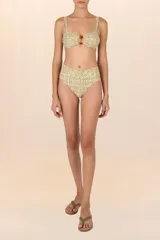 Top de bikini bandeau con estampado floral en tonos amarillo y lila, con detalle de cuentas marrones en el centro. Breteles anchos y ajustables.