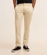 Pantalón de vestir marrón, de corte skinny, con bolsillos laterales y traseros. Se ajusta a la cintura con cinturón de cuero marrón.