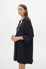 Camisola negra larga tipo vestido, de manga tres cuartos y cuello camisero. Tiene botones delanteros ocultos.