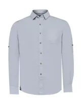 Camisa celeste de manga larga con cuello camisero, cierre con botones de madera y bolsillo en el pecho.
