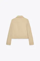 Chaqueta color beige de cuello solapa y manga larga con hombreras acabada en puño. Presenta bolsillos laterales y falso bolsillo de vivo en pecho. Cierre frontal con botones.