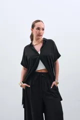 Camisola negra de tencel con cuello camisero, manga corta y cierre frontal con botones.