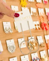 Aretes colgantes largos plateados, con un poste delgado que cae en un aro grande.