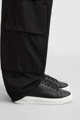 Zapatillas urbanas de cuero sintético negro con cordones y suela blanca de goma con volumen.