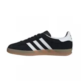 Zapatillas Adidas Gazelle Indoor negras con las tres tiras blancas y suela color caramelo.