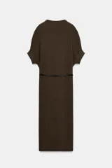 Vestido negro de tejido de punto, corte midi y silueta holgada, con cuello alto acanalado y mangas cortas tipo murciélago. Se ajusta a la cintura con un cinturón fino de efecto piel negro con hebilla dorada en forma de C.