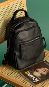 Mochila urbana negra de símil cuero con dos bolsillos frontales, bolsillo principal de gran capacidad, dos bolsillos internos con cierre y uno abierto, bolsillos laterales abiertos, asa de mano y correas regulables.