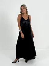 Vestido largo negro de breteles finos y escote en V, confeccionado en tela nacarada.