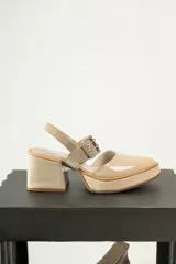 Zapato de cuero color beige con punta redondeada, taco cuadrado y correa con hebilla.