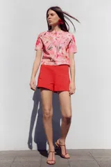 Bermuda roja de tiro alto con bolsillos delanteros de vivo y cierre lateral con cremallera oculta.