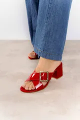 Sandalia tipo zueco de cuero vacuno color negro charol, con capellada ancha cruzada y hebilla metálica dorada. Taco ancho de 6 cm.