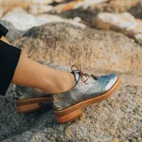 Zapato acordonado color bronce de cuero vacuno con perforaciones decorativas, taco de madera con folia en cuero de 4cm y entre suela de goma de 1,5cm. Horma de punta redonda y cómoda.